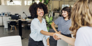 CV Alternance : une femme souriante sert la main à une autre, hors champ, dans un bureau en entreprise